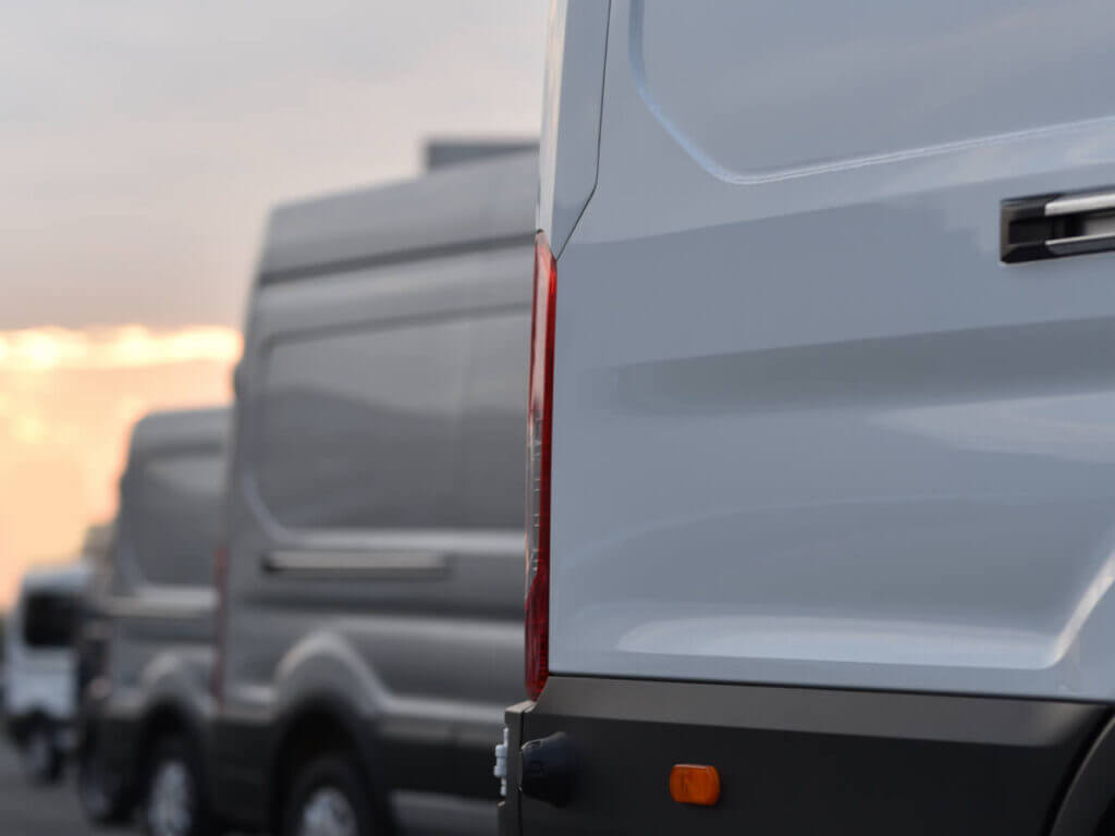 The back bumper of three white cars, lined up from the foreground to the background