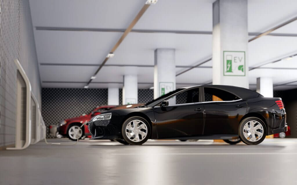 A black car in a parking garage being charged by an electric charger