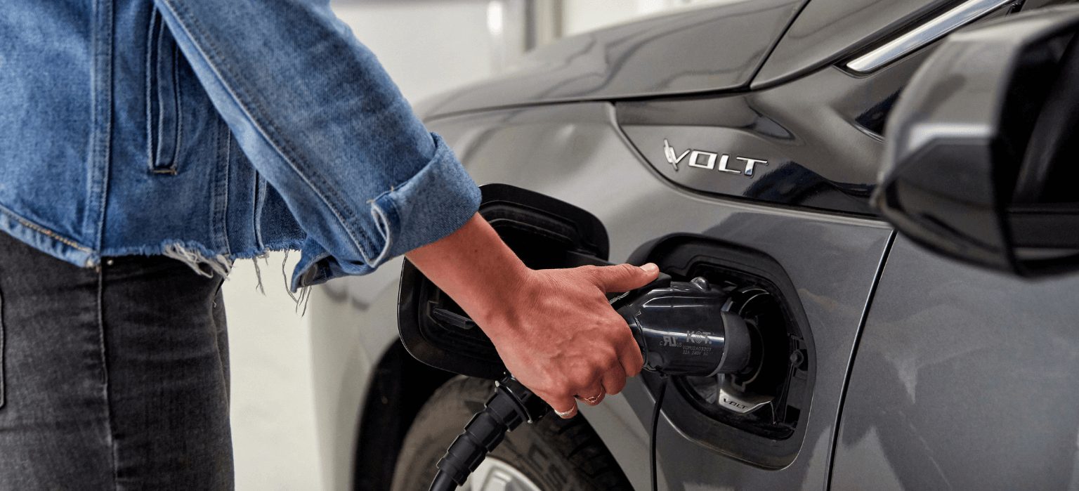 Woman's hand plugging charger into EV.