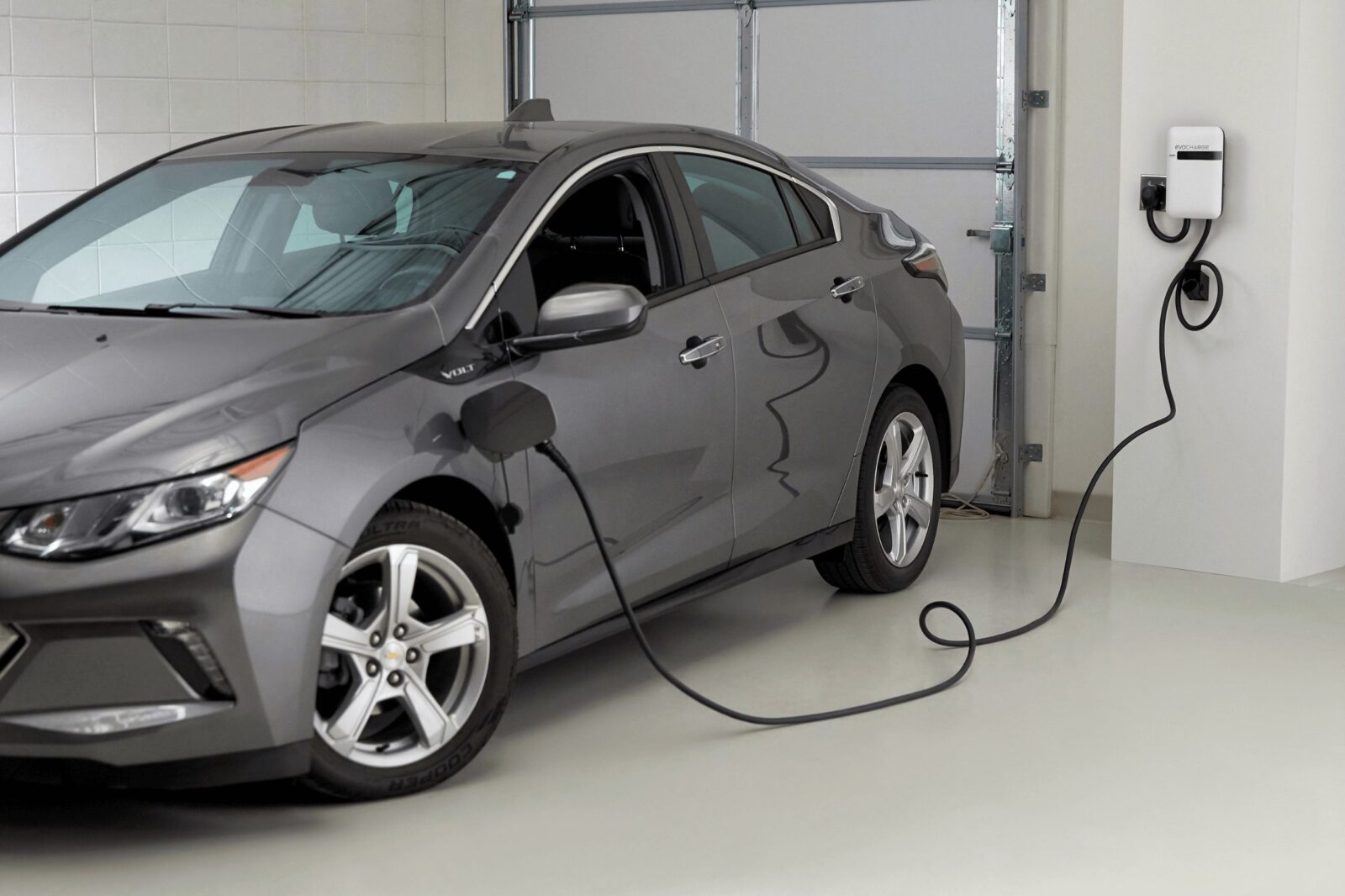 A car charges in a white, closed garage