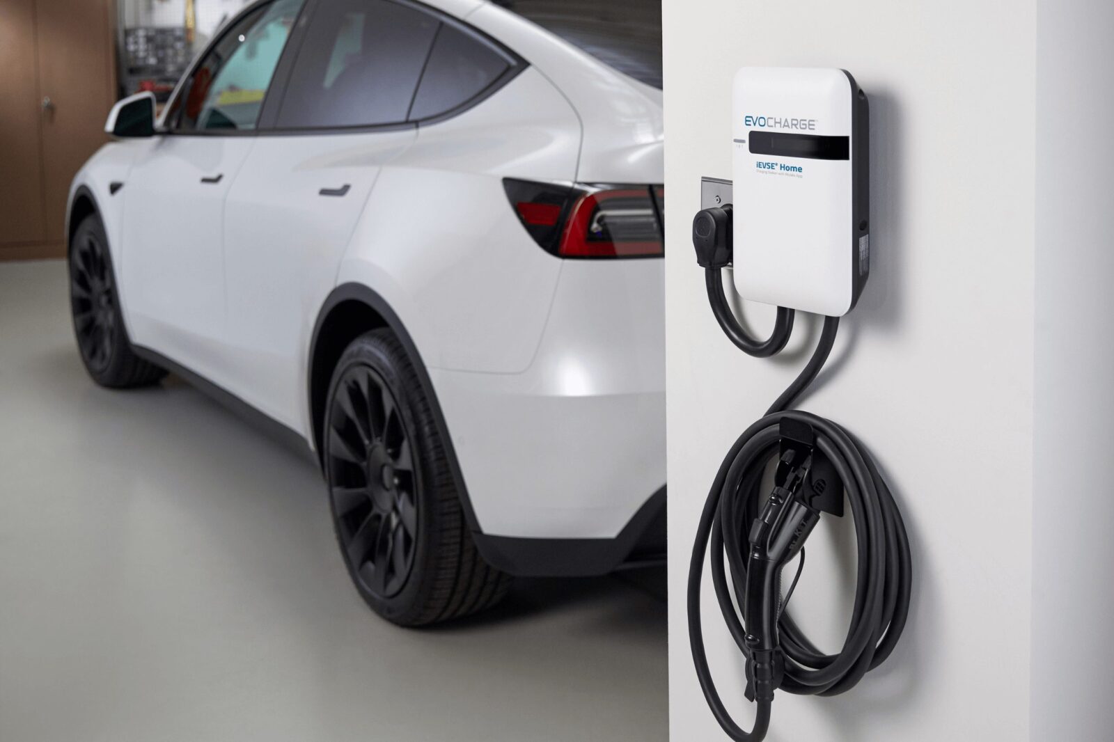 A car parked in a garage with the EvoCharge mounted to the wall in the forground.