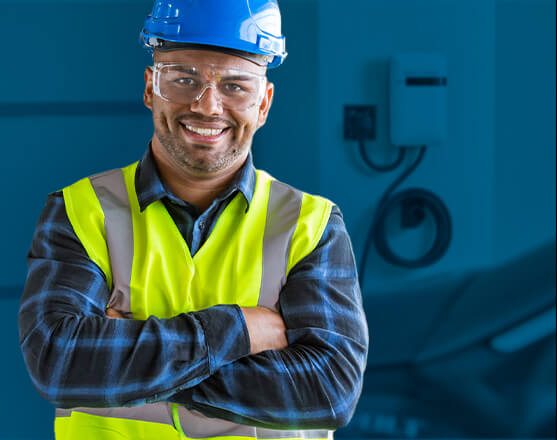 A construction worker smiling with crossed arms in front of a blue background.