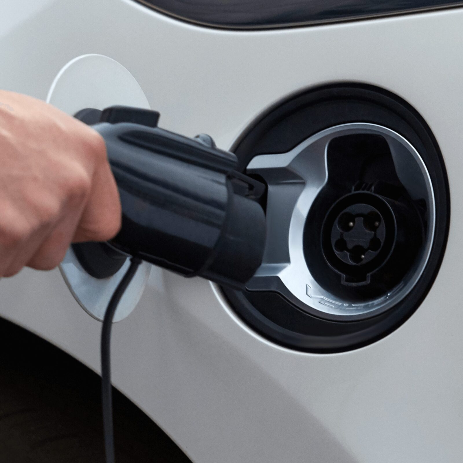 A closeup of someone plugging in their electric vehicle