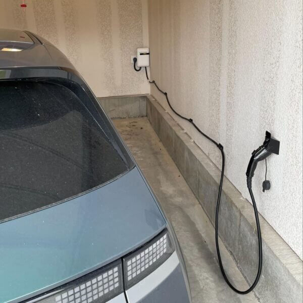 A garage with an EvoCharge mounted to the lower wall. The charge cord is extended and mounted into a clip for easy charging.