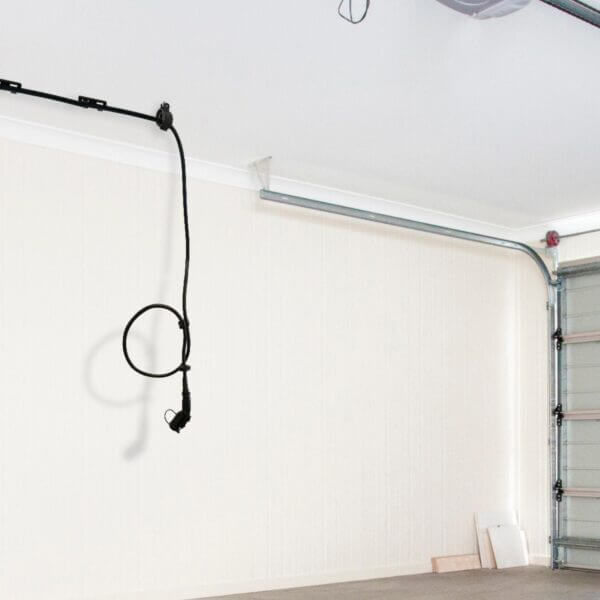 An electric vehicle plug hangs from the garage ceiling